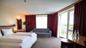A hotel room with two beds, a sofa, a desk, and a balcony with red curtains. - Best Western Conference Airporthotel Frankfurt Mörfelden (Moerfelden-Walldorf)
