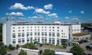 A multi-story building with a flat roof, numerous windows, and a parking area in front. - Best Western Conference Airporthotel Frankfurt Mörfelden (Moerfelden-Walldorf)