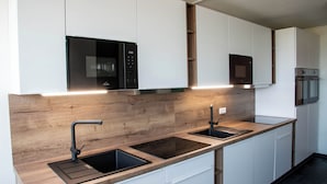 A modern kitchen with two sinks, a microwave, and a built-in oven. - Best Western Conference Airporthotel Frankfurt Mörfelden (Moerfelden-Walldorf)