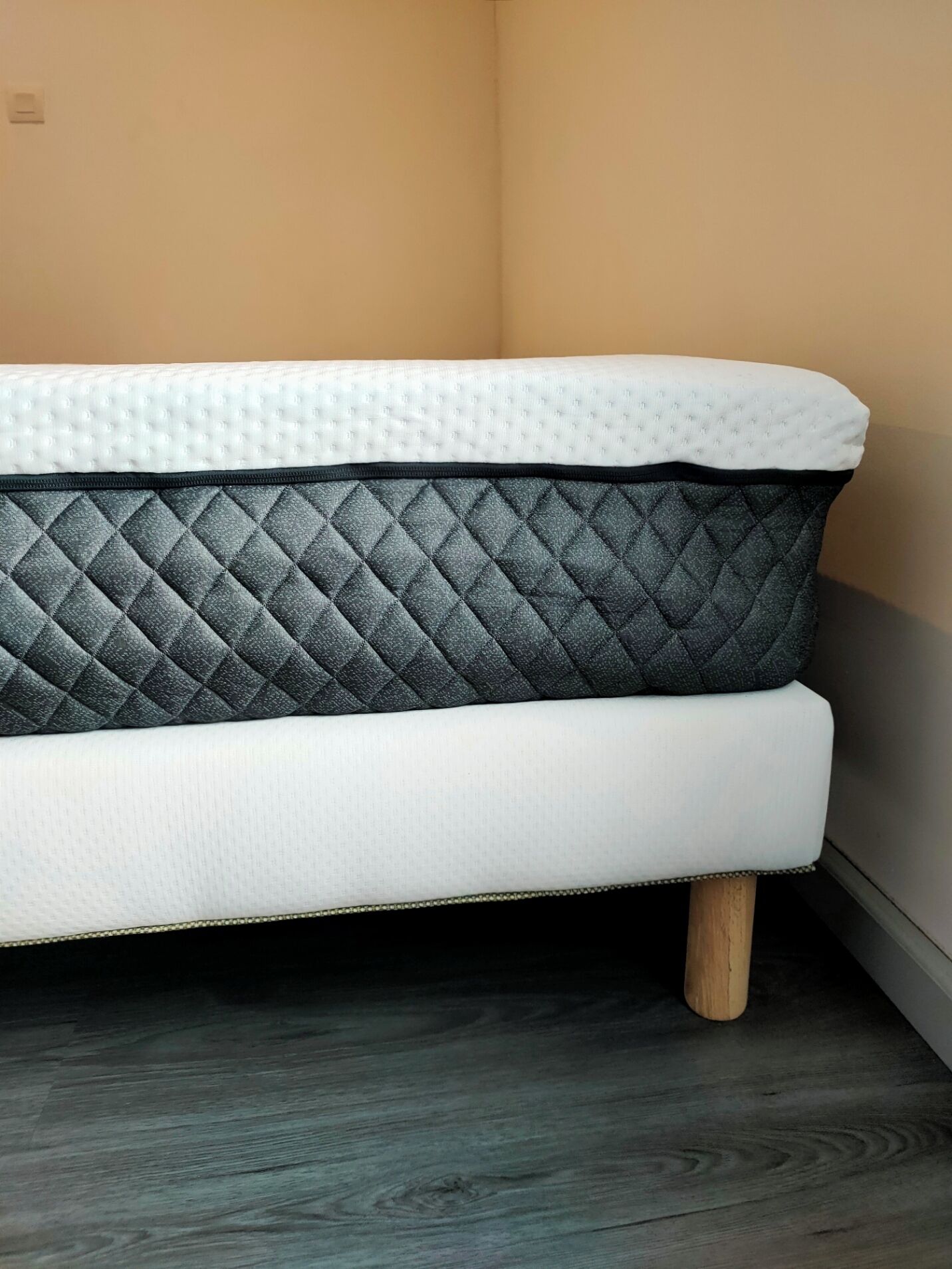 Een bed met een gewatteerd matras en houten poten.