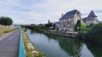 Un canal surmonté d’un pont, une promenade pavée et des bâtiments en pierre à l’architecture traditionnelle.