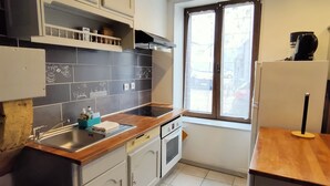 A compact kitchen with white cabinets, a wooden countertop, and a window providing natural light.