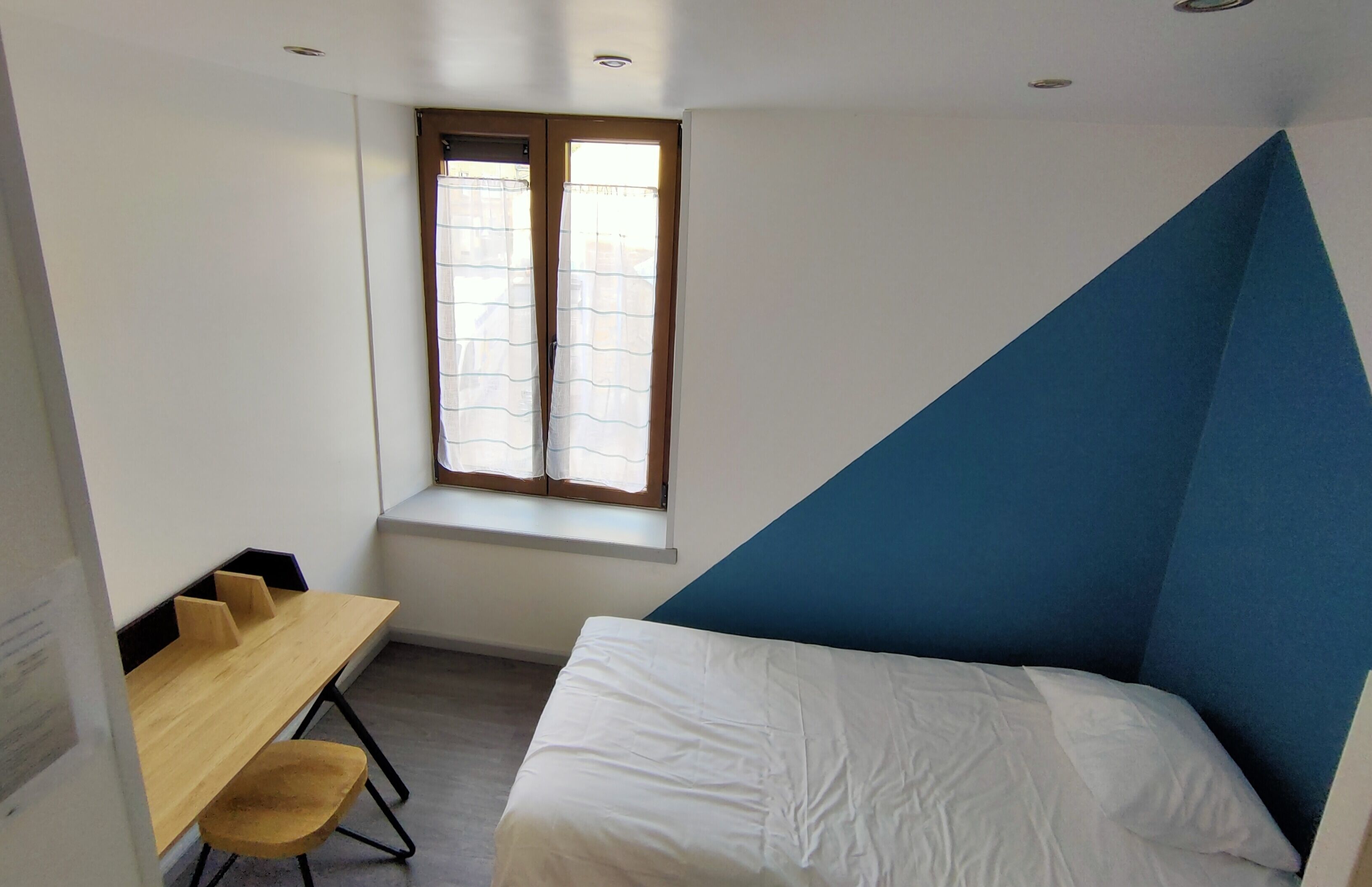 Een kamer met een bed, een bureau en een raam.