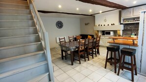 A kitchen with a dining area, a clock on the wall, and a staircase.