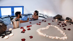 Ett par i ett bubbelbad, med rosenblad och ljus utspridda på golvet.