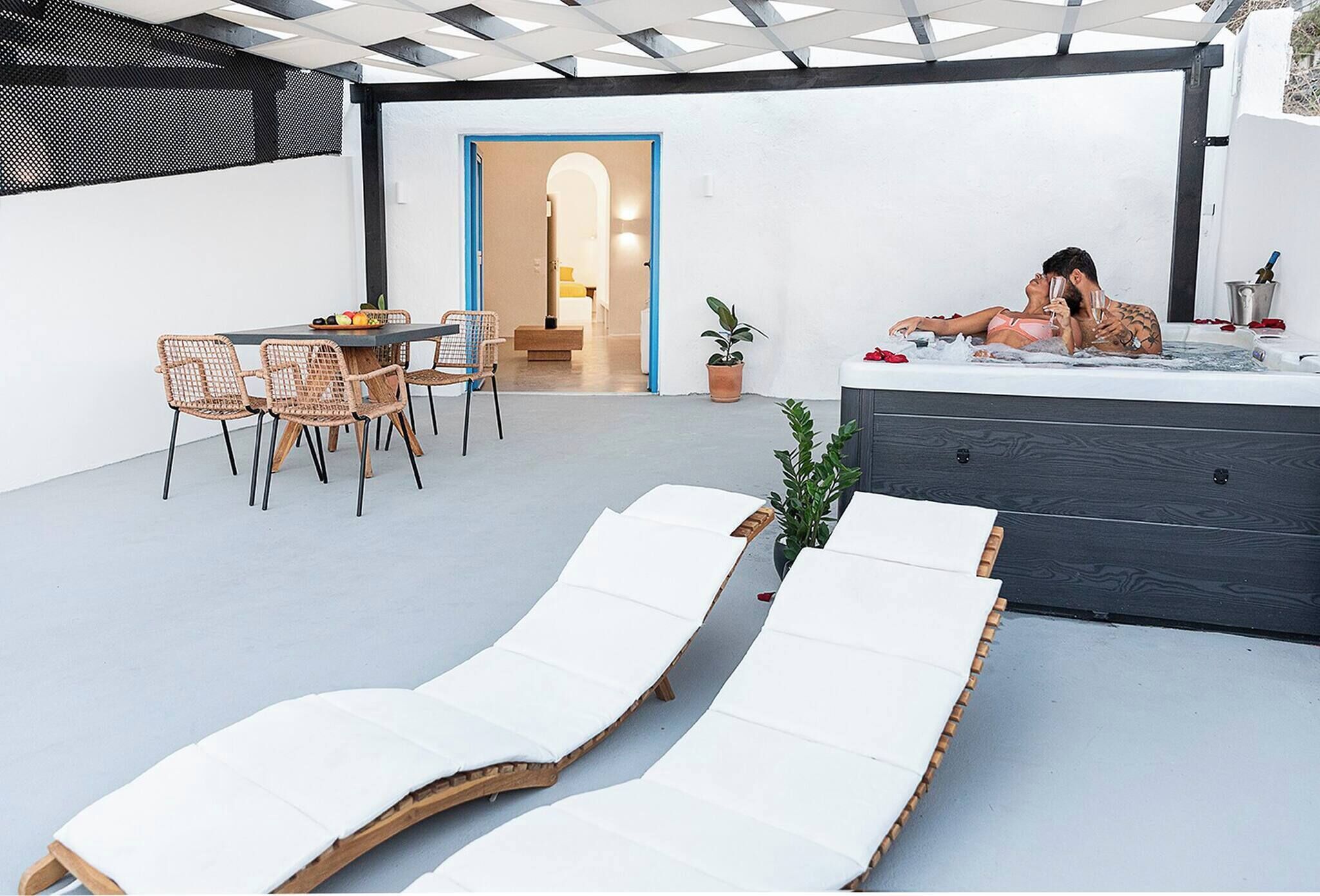 A modern outdoor patio with lounge chairs, a dining area, and a hot tub.