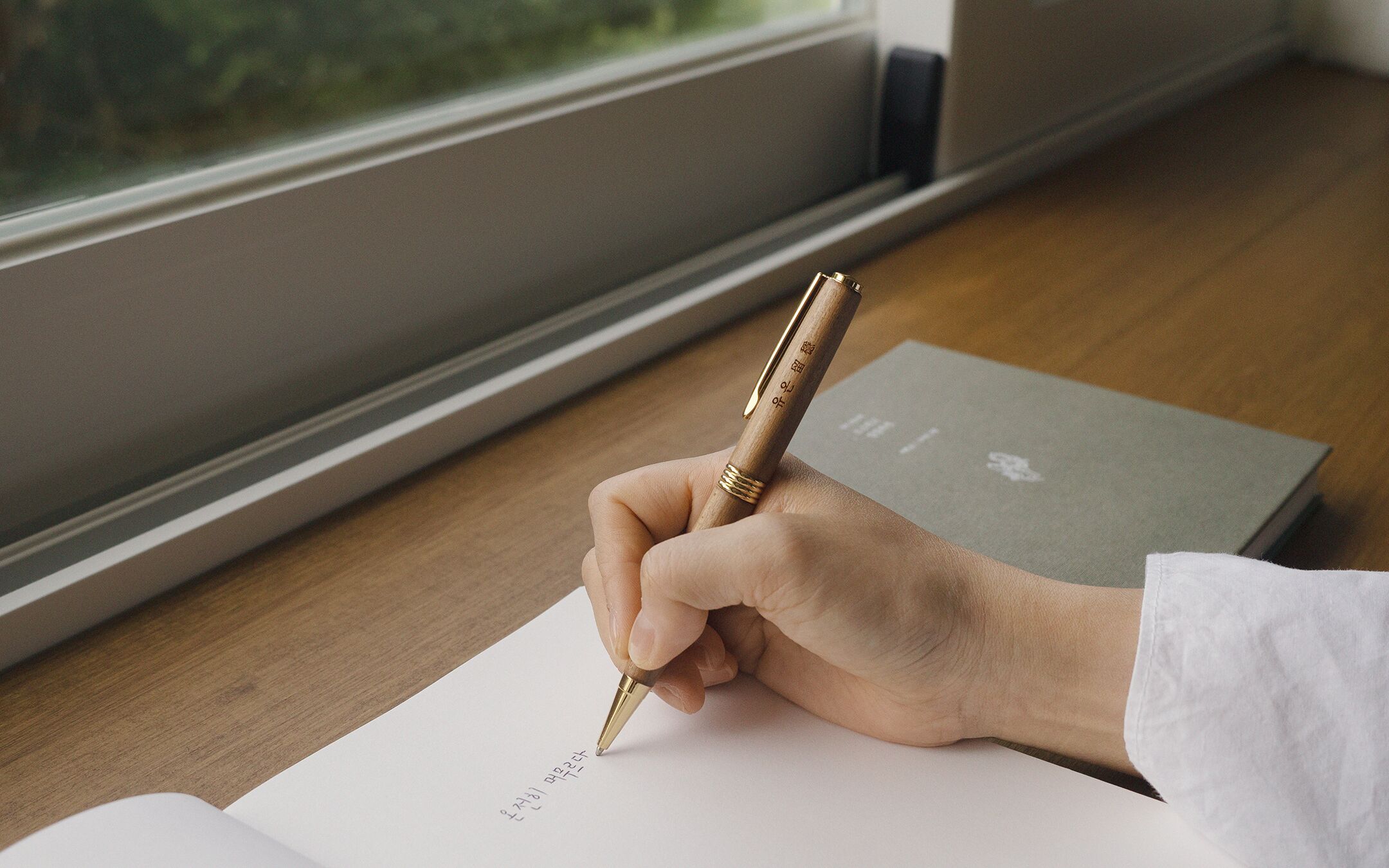 A hand holding a pen, writing on a piece of paper.