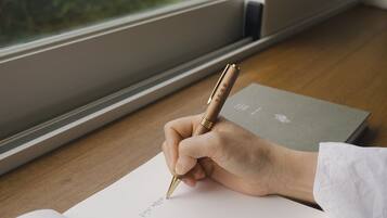 A hand holding a pen, writing on a piece of paper.