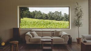 A living room with a large window, a beige sofa, a small wooden table, and a potted plant. - uonstay (Gyeongju)