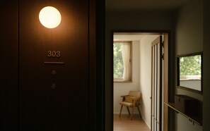 A room with a wooden door marked '303', a small window, and a chair. - uonstay (Gyeongju)