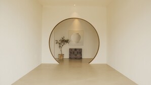 A minimalist interior with a large circular archway, a potted plant, and a framed artwork on the wall. - uonstay (Gyeongju)
