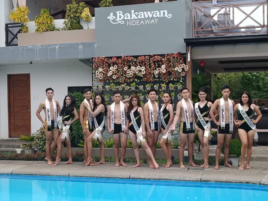 Un grupo de personas de pie junto a una piscina, con un cartel que dice 'Bakawan Hideaway' al fondo.