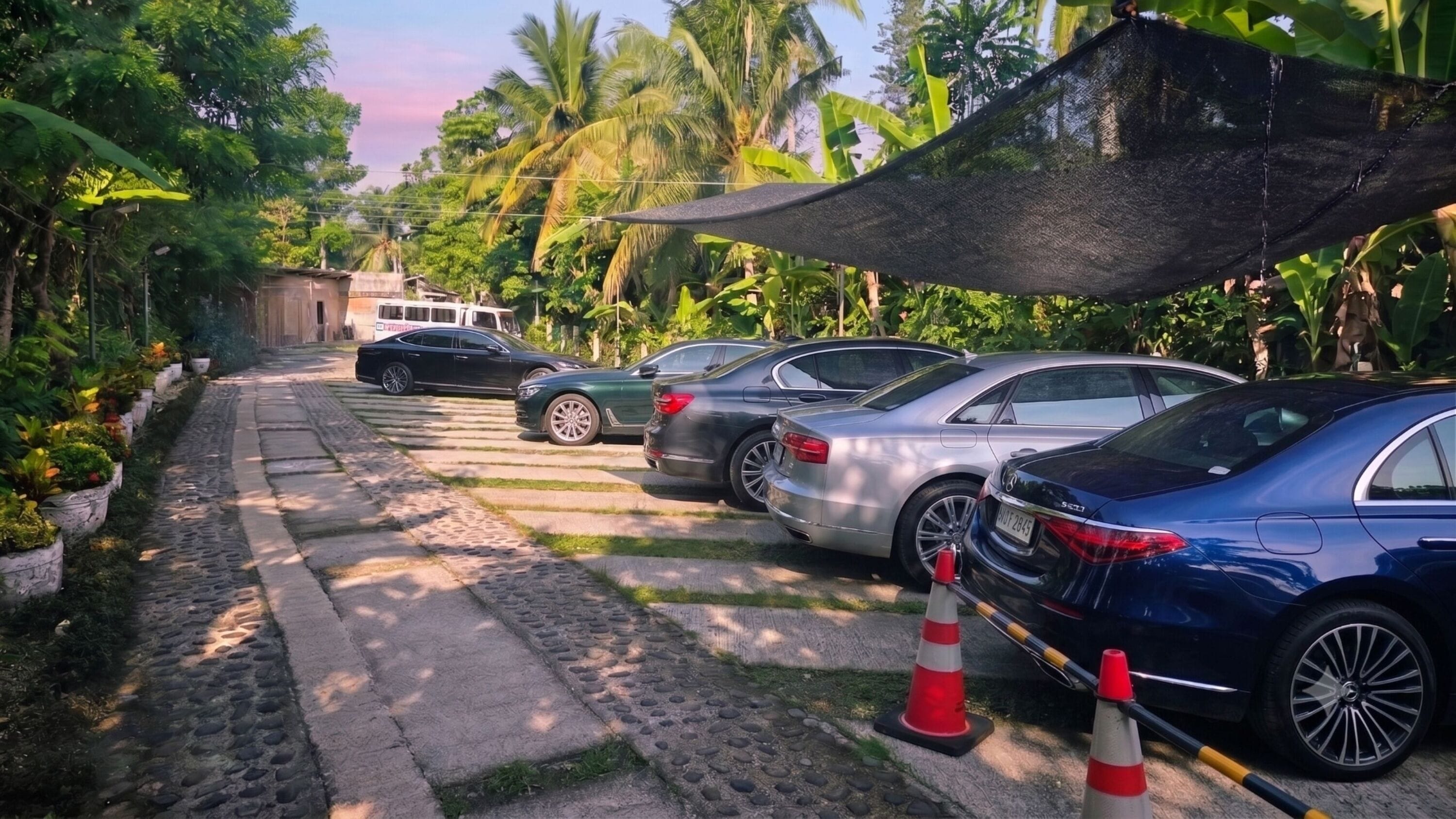Ein Parkplatz mit Autos, einem Kiesweg und einem schattigen Bereich mit einer Markise.