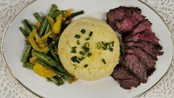 A plate with mashed potatoes, green beans, and sliced beef.