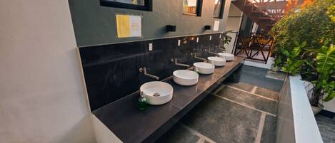 Un baño moderno con varios lavamanos y un espejo grande.