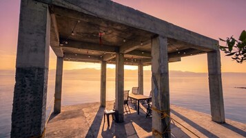Una estructura de concreto con una mesa y sillas, con vista a una masa de agua tranquila.