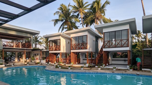 Ein modernes Resort mit Swimmingpool, Holzbalkonen und Palmen.