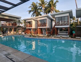 Un resort moderno con piscina, balcones de madera y palmeras.