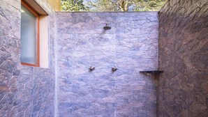 A stone shower enclosure with a window and two faucets.