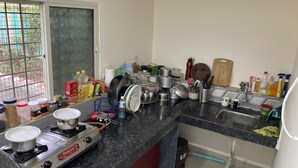 Cozinha equipada com fogão a gás, pia e diversos utensílios e recipientes.