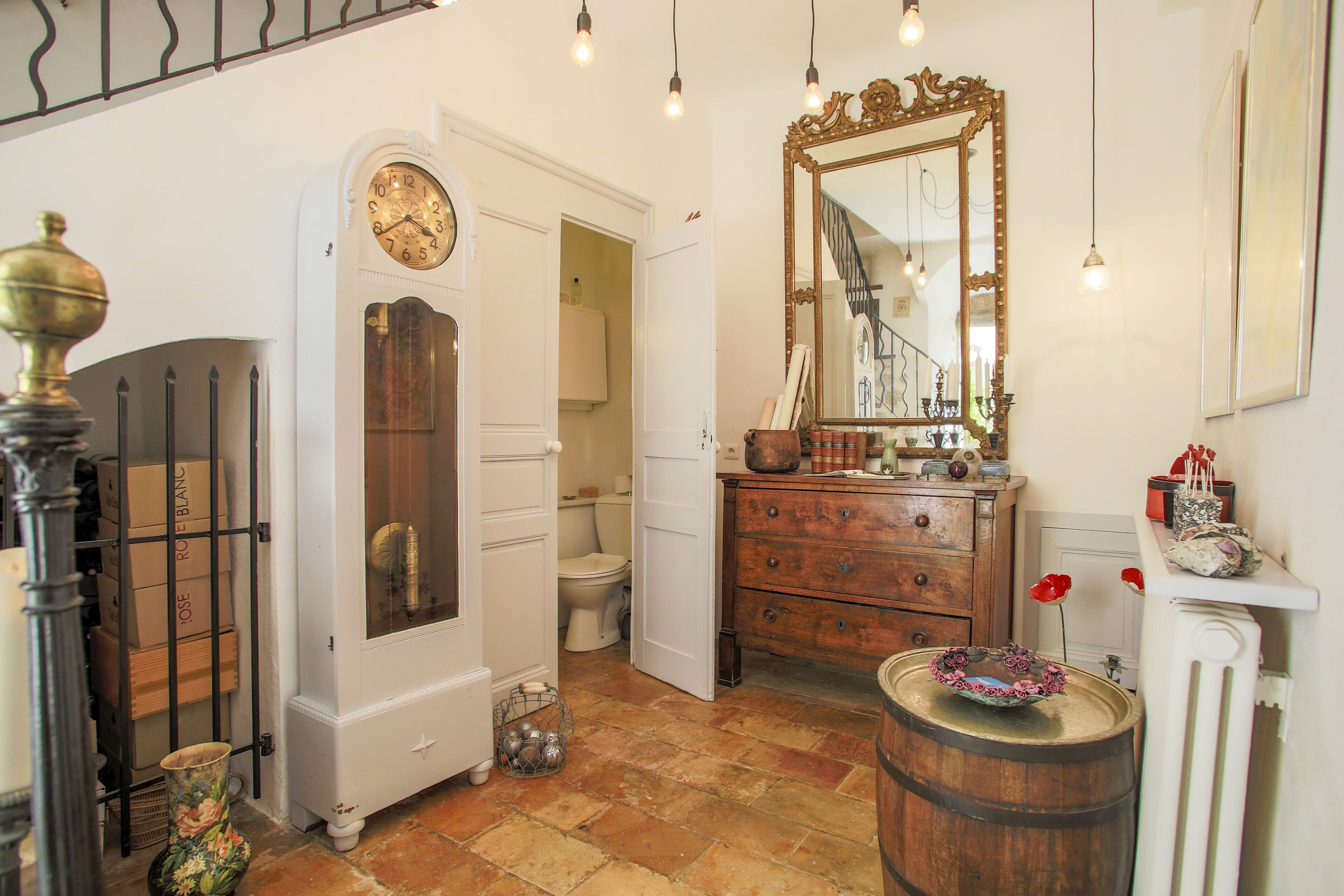 A traditional room with a wooden floor, a white door, a wooden dresser, a mirror, and a clock.