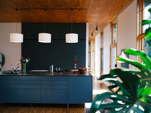 A modern kitchen with a central island, pendant lights, and a large window providing natural light.