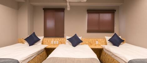A hotel room with two beds, wooden headboards, white bedding, and a ceiling air conditioner.