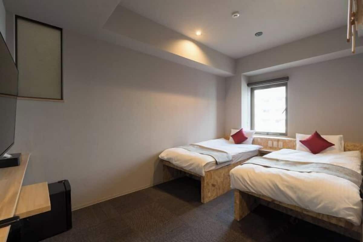 A room with two beds, a desk, and a window.