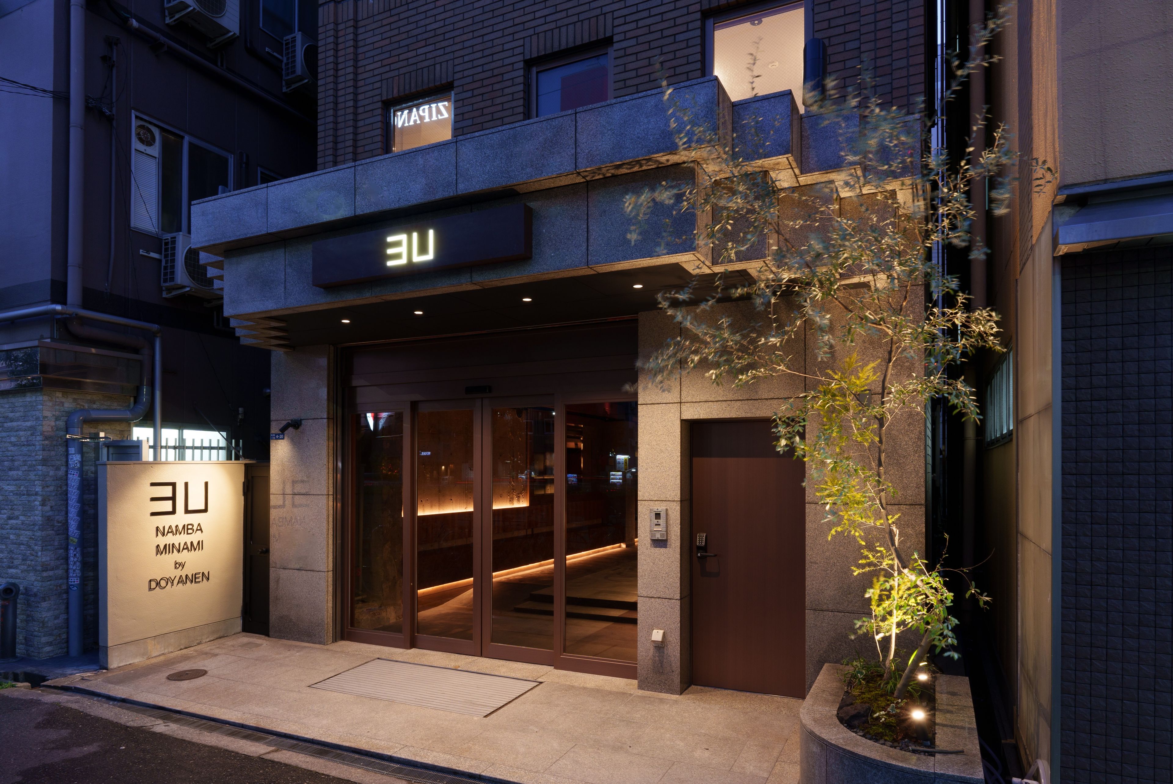 Un bâtiment sur lequel on peut lire l’inscription « UE », et en dessous, une plus petite inscription indiquant « Namba Minami by Doyanmen ».