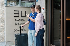 Two people standing in front of a building with a sign that reads 'Namba Minami' and 'Doyanmen.' - 3U NAMBA MINAMI - DOYANEN HOTELS (Osaka)