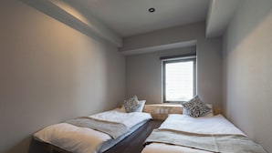 A bedroom with two beds, a window, and a wooden bench. - 3U NAMBA MINAMI - DOYANEN HOTELS (Osaka)