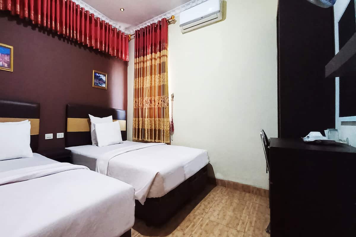 Ein Hotelzimmer mit zwei Betten, einem Schreibtisch und einem Fernseher.