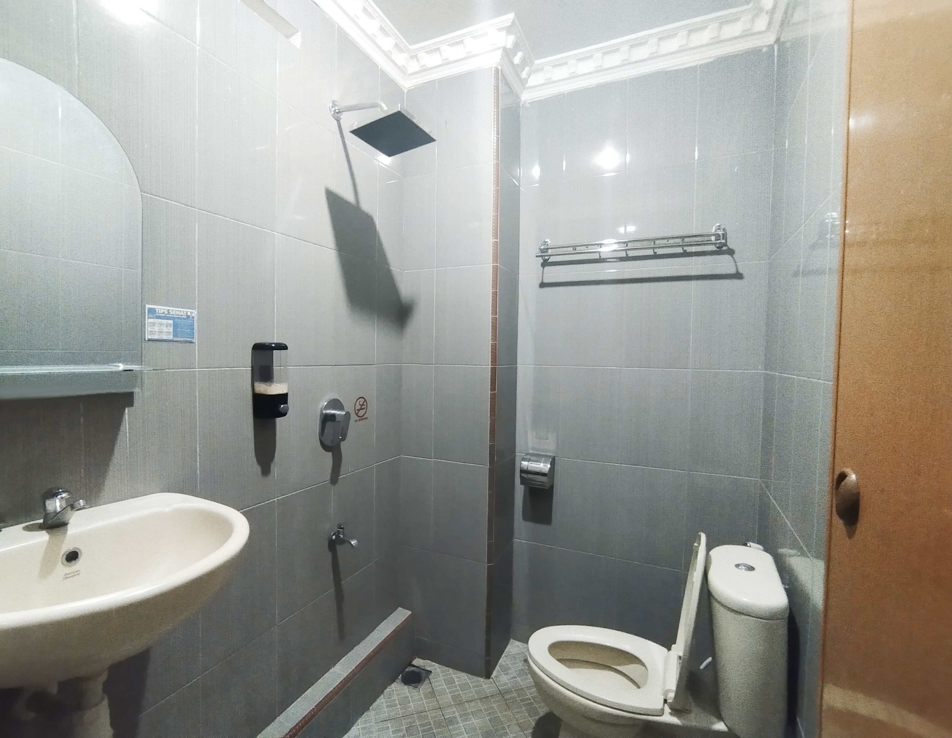 A small, modern bathroom with a sink, toilet, and shower.