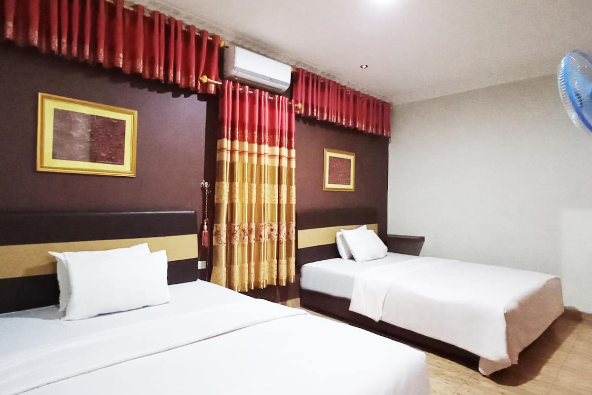 Ein Hotelzimmer mit zwei Betten, einem roten Vorhang, einer weißen Klimaanlage und einem blauen Ventilator.