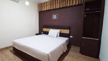 Ein ordentlich bezogenes Bett mit einem hölzernen Kopfteil, einem Nachttisch und einem Kleiderschrank.