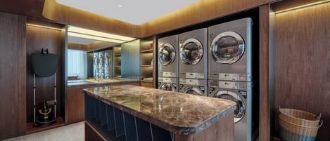 A modern bathroom with a marble countertop, multiple washing machines, and a large mirror.