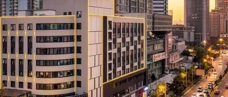 A multi-story hotel with a modern design, featuring a prominent entrance and a parking area.
