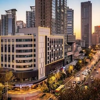 Ein mehrstöckiges Hotel mit modernem Design, das eine markante Eingangspartei und einen Parkbereich aufweist.