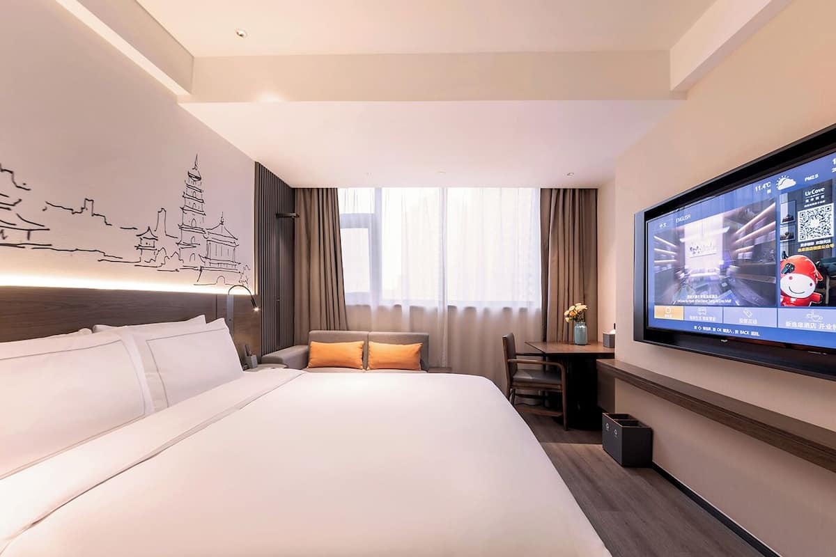 Una habitación de hotel con una cama grande, un escritorio, un televisor y un mural en la pared.