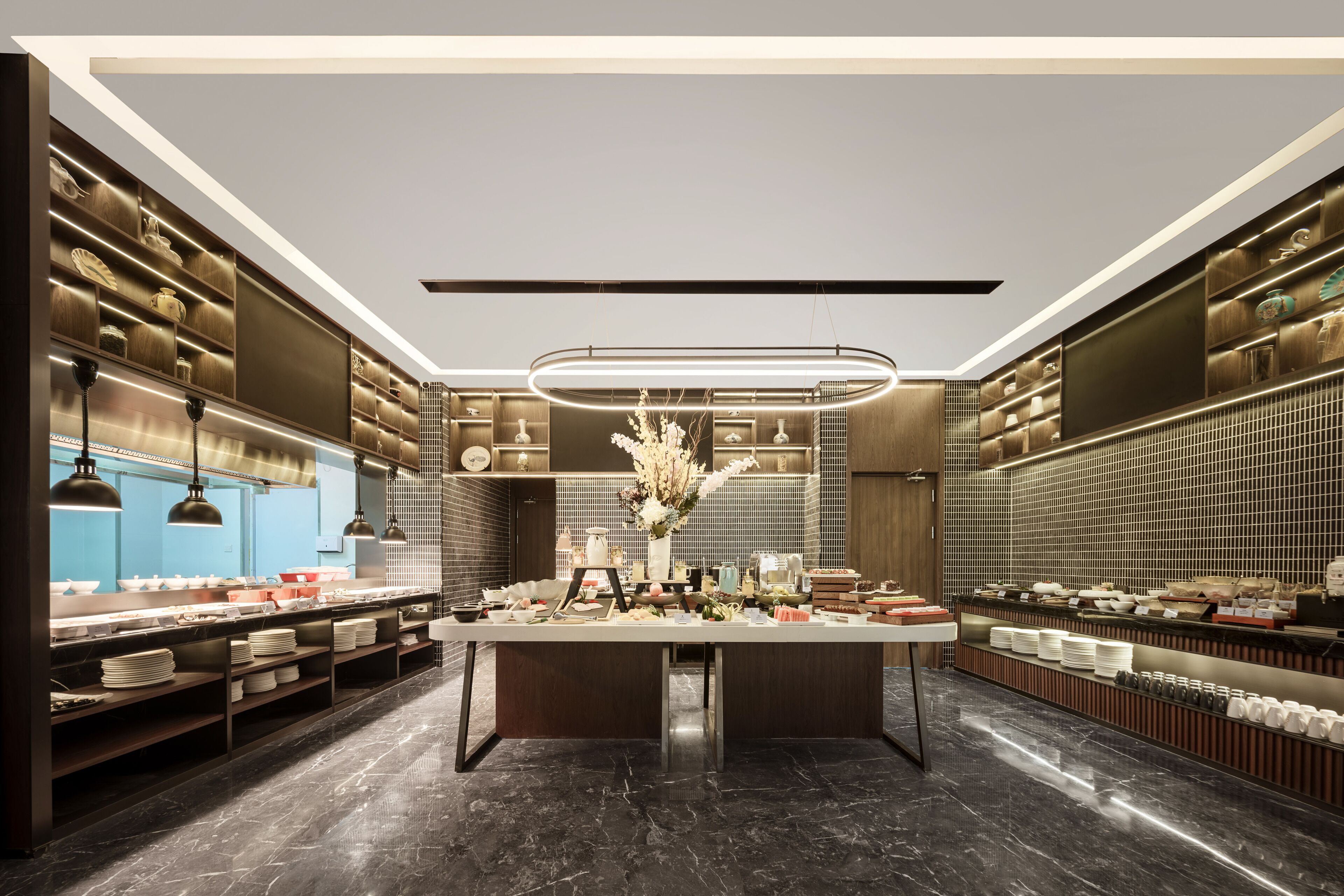 A modern kitchen with a central island, built-in shelves, and pendant lighting.