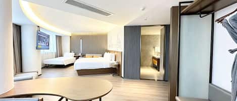 Quarto de hotel com cama, mesas de cabeceira, escrivaninha e área de estar.
