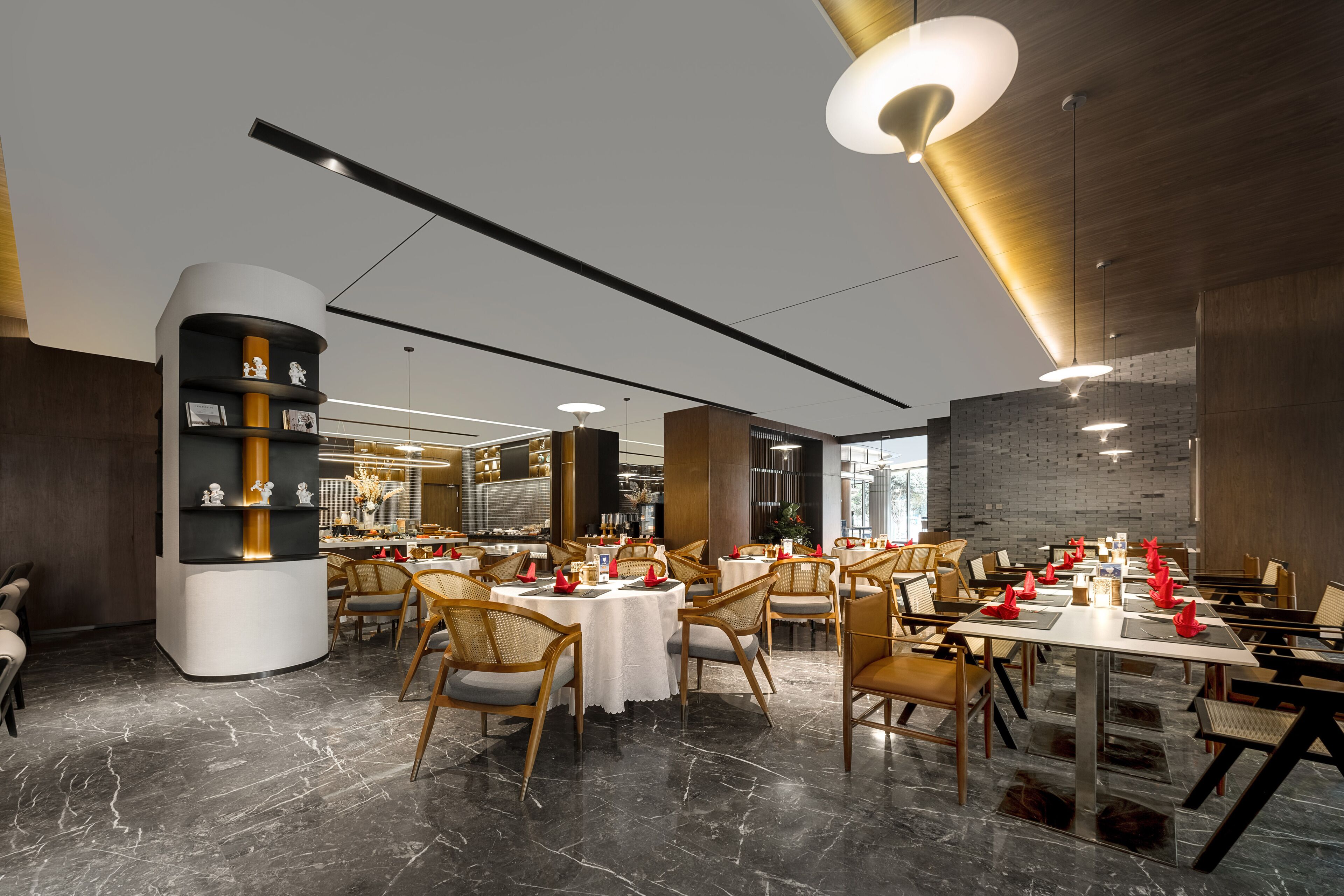 Un comedor moderno con mesas redondas, sillas de madera y una estantería blanca en el centro.