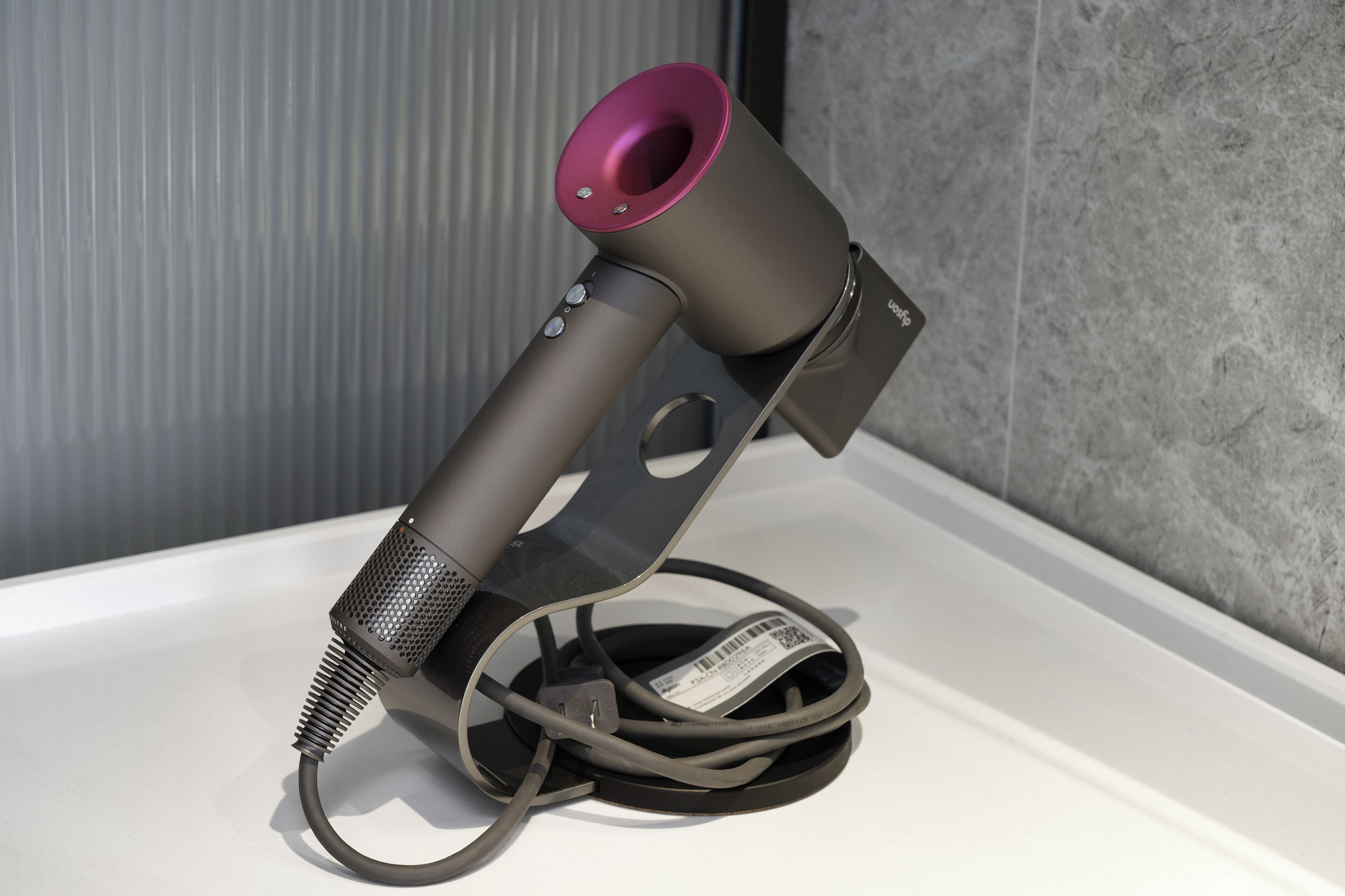 A hair dryer with a cord and a label on a white surface.