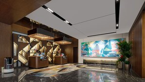 Eine moderne Lobby mit einer Rezeption, einer Kaffeemaschine, einem farbenfrohen abstrakten Gemälde und einem polierten Marmorboden.