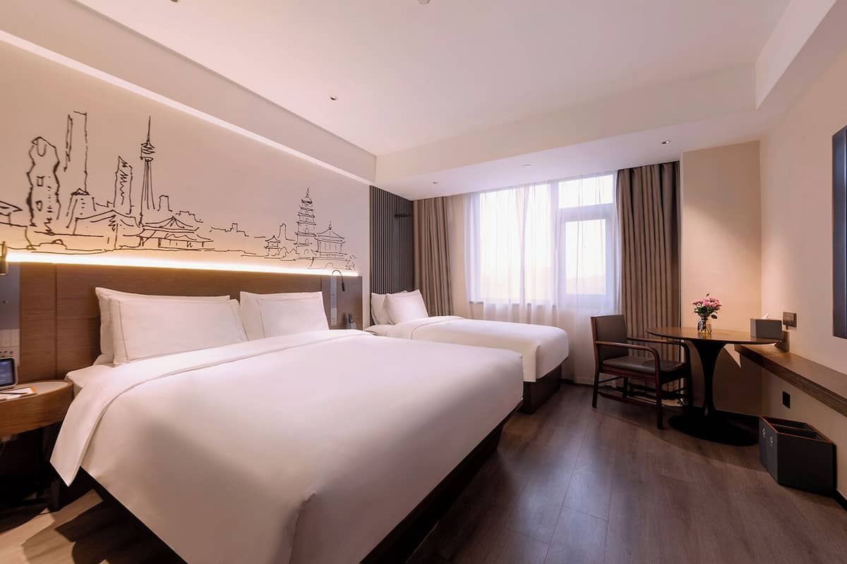 Habitación de hotel con dos camas, un escritorio y una silla.