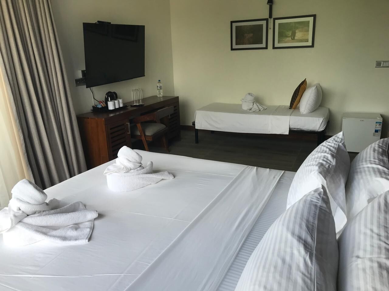 Et hotelværelse med to senge, et skrivebord, et fjernsyn og et lille siddeområde.