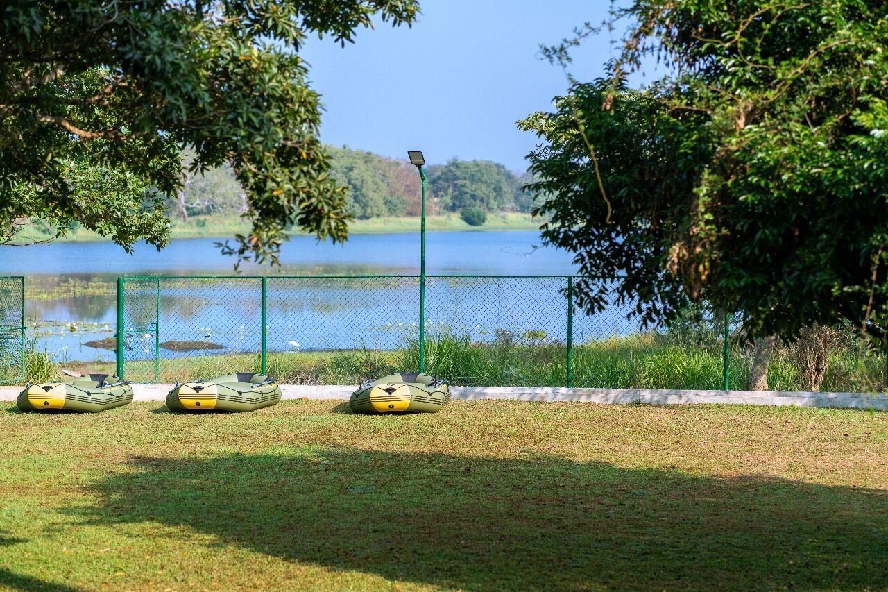 Un'area recintata con tre barche verdi e gialle, una vista libera su un lago e un lampione.
