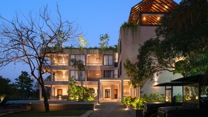 Un hotel moderno con un patio central, varios balcones y una piscina.