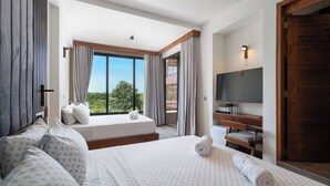 Habitación de hotel con dos camas, televisión, escritorio y vista al exterior.