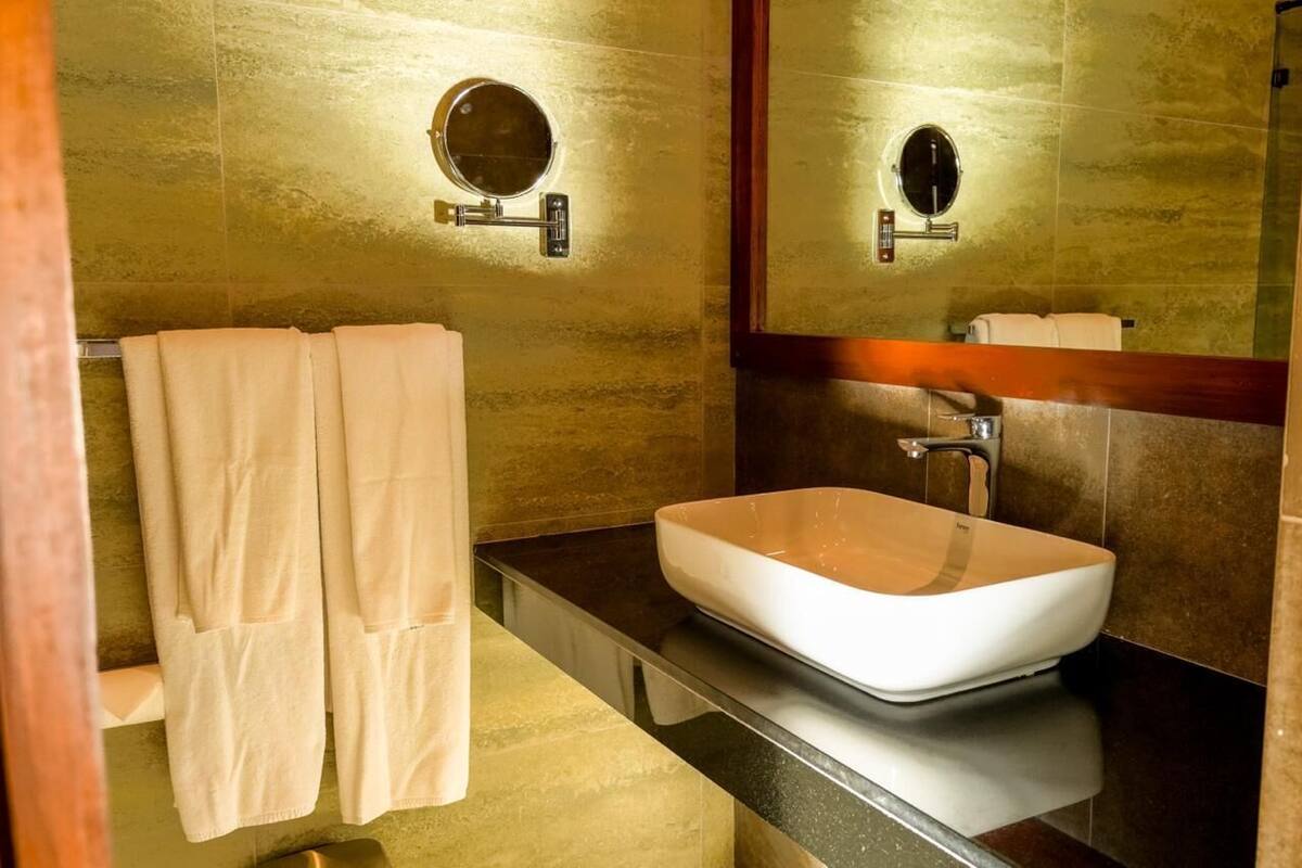A bathroom with a large mirror, a white sink, and two towels hanging on the wall.